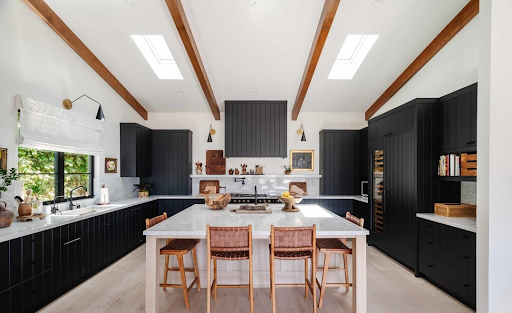 a wood beamed open kitchen with black cupboards